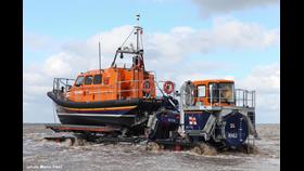A Lifeboat on her carriage is pushed into the sea by a tractor unit.