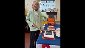Blyth RNLI Volunteer Jean Fowler at her 75 years of volunteering celebration. Jean is holding a knife ready to cut her cakes