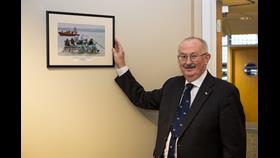 Colin Watson posing for a photo at Poole HQ along with a photo he had taken of the Cranfield Raft Race