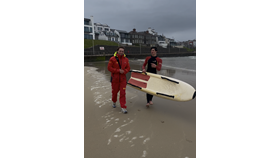 RNLI lifeguards Cameron Leighton & Ethan Hill returning from the sea after assisting five children caught by offshore winds, out at sea