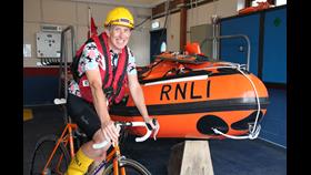 Dan is on his bicycle in front of Shoreham's inshore lifeboat.