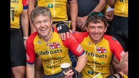Two men in lifeboat cycling jerseys celebrating their mammoth achievement.