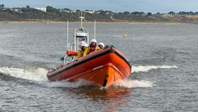 An orange RNLI rib with four crew aboard make their way to Christchurch Harbour