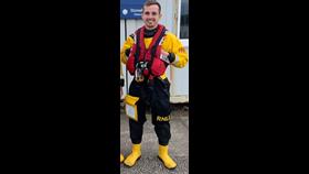 New helm Jamie Longfield in his RNLI yellow and black dry suit, with red RNLI life jacket