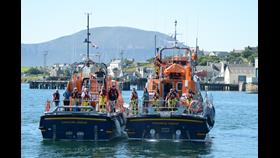 Crews of two lifeboats, viewed from the stern, line up to pose for a photo