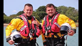 Brothers James and Mark stand by the water looking at the camera in their RNLI kit