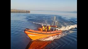 Inshore lifeboat with four crew on board on calm water on a sunny day