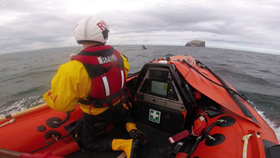 Lifeboat crewmember observes inflatable kayak from the D class lifeboat with the Bass Rock in the background