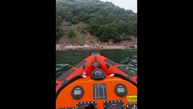 Plymouth RNLI volunteers providing casualty care to injured man after falling from coastal path.