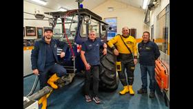 The four new launch vehicle drivers standing inside the boathouse beside the modified tractor which is used to push the lifeboat out to sea.