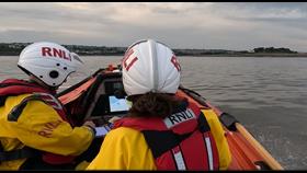 Two crew members looking at a screen to plot a course