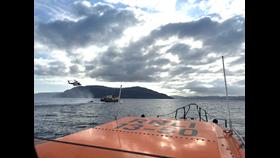 In the early morning light, a Coastguard rescue helicopter hovers above a small cruise ship in a photo taken from the Oban lifeboat.