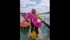 Crew member Will Rowell standing with the rescued red balloon