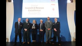 Six representatives from the four RNLI lifeboat stations stood in a line on stage with their award at a ceremony in London