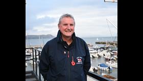 Man in blue jacket in front of harbour