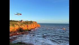 Exmouth RNLI Inshore and All-weather lifeboats working alongside H.M. Coastguard helicopter to reach casualties on rocks