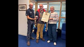 Cliff Thomas being awarded medal and certificate for 50 years volunteering service at Pwllheli RNLI. From left to right in the photo, Andy Vowell, Pwllheli RNLI Lifeboat Operations Manager, Cliff Thomas and Carolyn Greene, RNLI Chief People Officer.