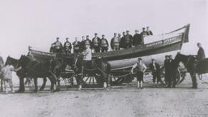 Hunstanton crew onboard their Self Righting class lifeboat, Licensed Victualler, as she sits on her horse-drawn carriage on the beach. Circa 1900-1931.
