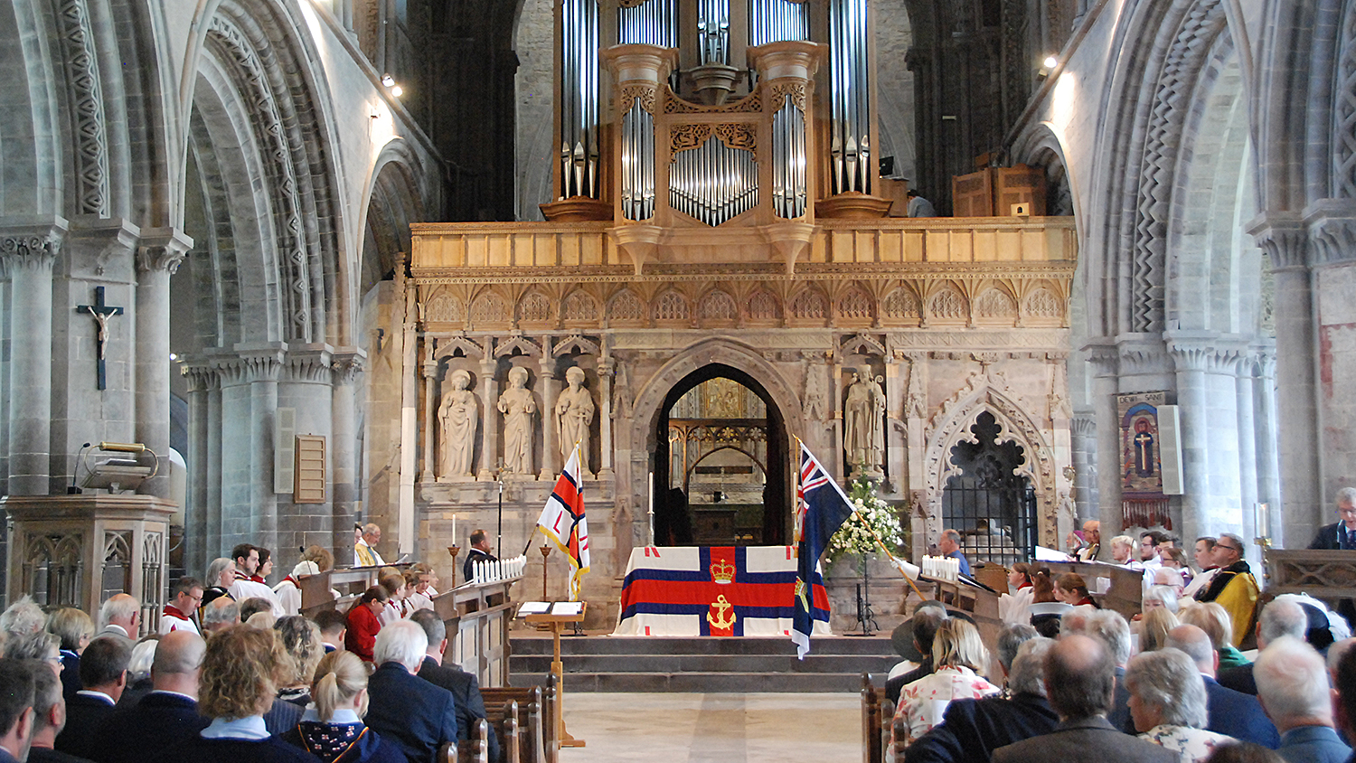 Inside St David’s Cathedral during the RNLI’s Thanksgiving Service on Sunday 14 July 2024. People are seated in pews and an RNLI flag is on display.