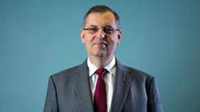 Headshot of Denis Woulfe against blue background