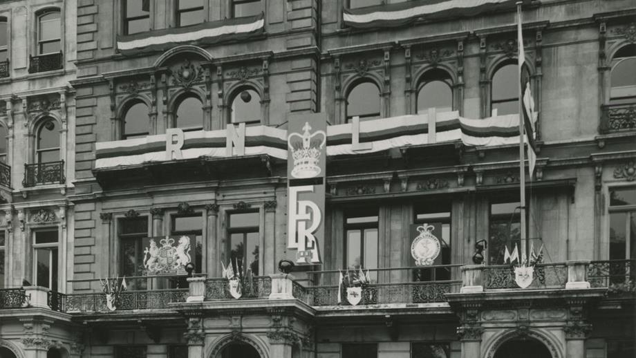 Black and white image of exterior of RNLI Head Office with coronation banner and flags