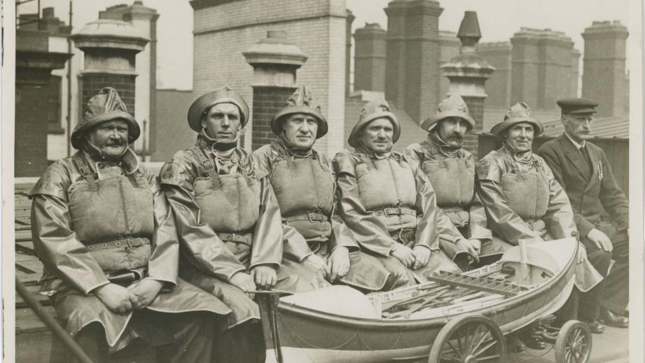 Black and white image of seven men in crew kit with medals