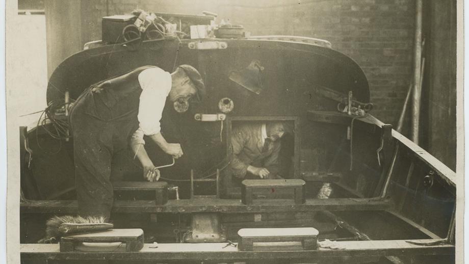 Black and white image of two men working on deck of lifeboat