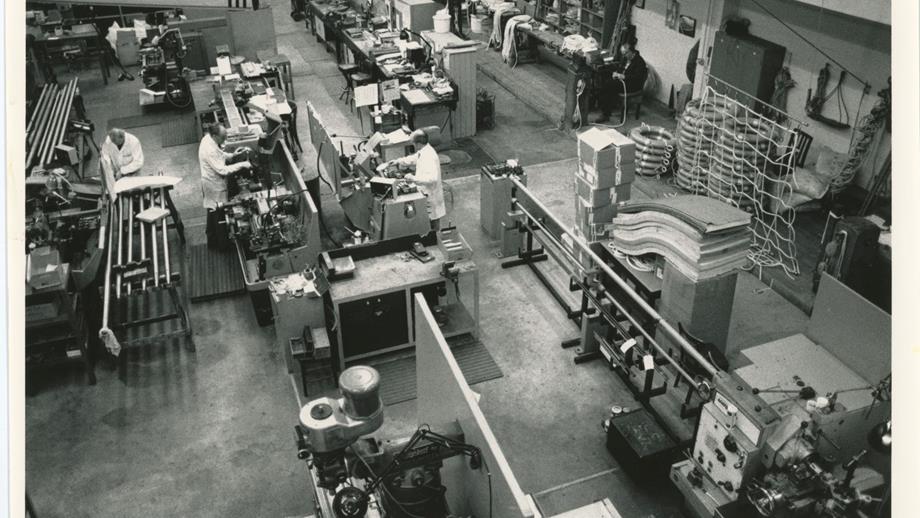 Black and white image of workshop interior and engineers at work
