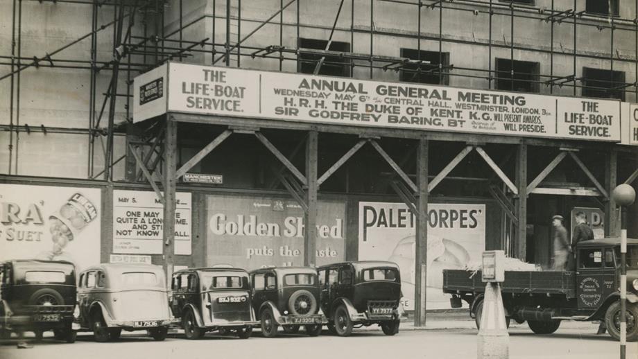 Black and white image of billboard for Annual General Meeting and cars