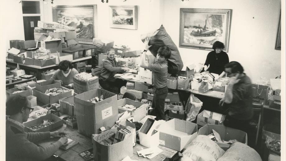 Black and white image of postcards and buttons being sorted