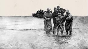 Second World War RNLI lifesavers helping a casualty through the water. The photo is in black and white.