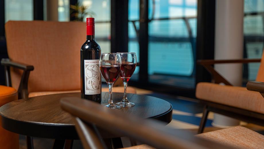 A bottle of wine accompanied by two glasses elegantly placed on a wooden table, inviting a moment of relaxation.