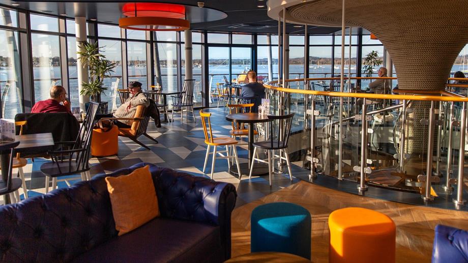 A large glass window at the RNLI slipway bar, offering stunning views of Poole Harbour and its vibrant surroundings.