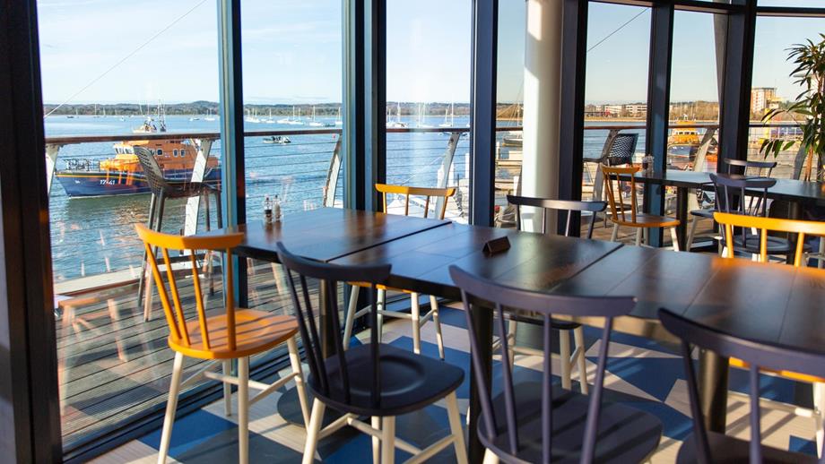 An elegant dining area with tables and chairs, offering a stunning waterfront view for a delightful dining experience.