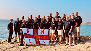 Group photo of Little and Broadhaven's crew holding an RNLI flag to celebrate 200 years
