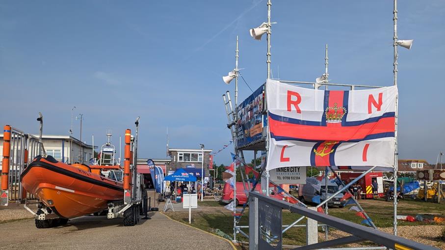Lifeboat outside lifeboat station with white and red RNLI flag next to it