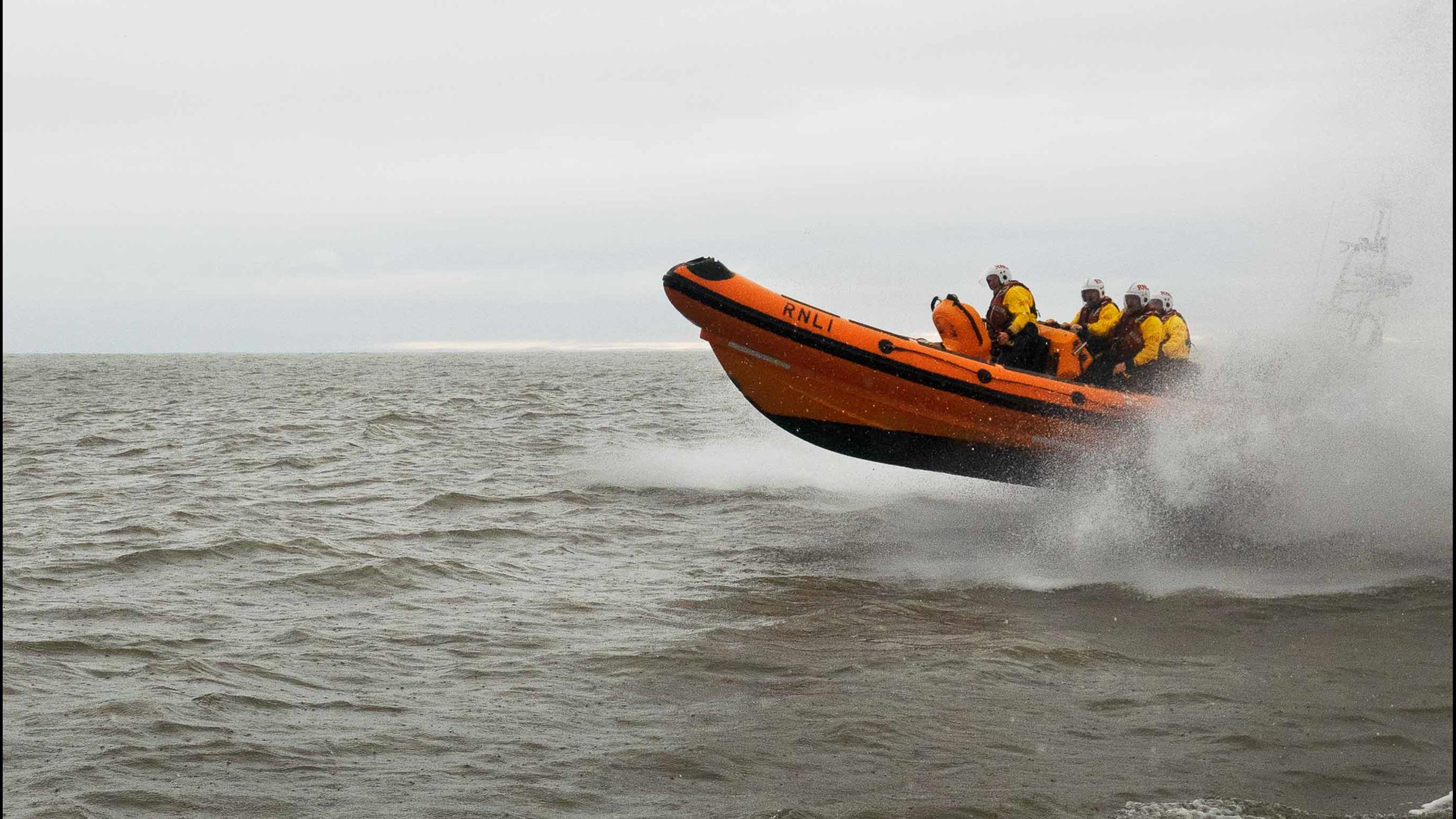 Arbroath's B class inshore lifeboat with four crew onboard glides across grey seas under overcast skies