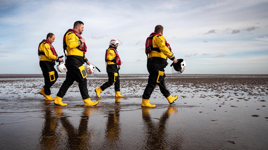 Cleethorpes lifeboat crew members walk along the beach