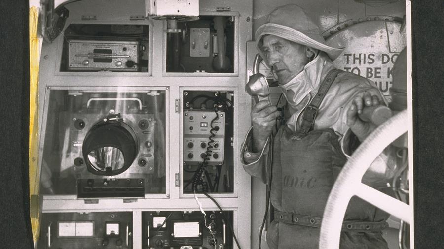 A photograph from the 1950s showing Lifeboat Mechanic Hodder from Plymouth RNLI using communication equipment aboard the lifeboat