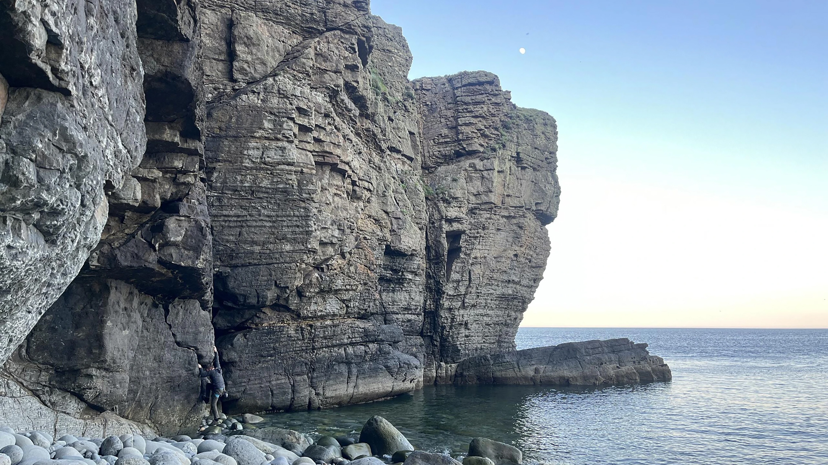A rocky ledge, jutting out into the sea from a pebbled beach