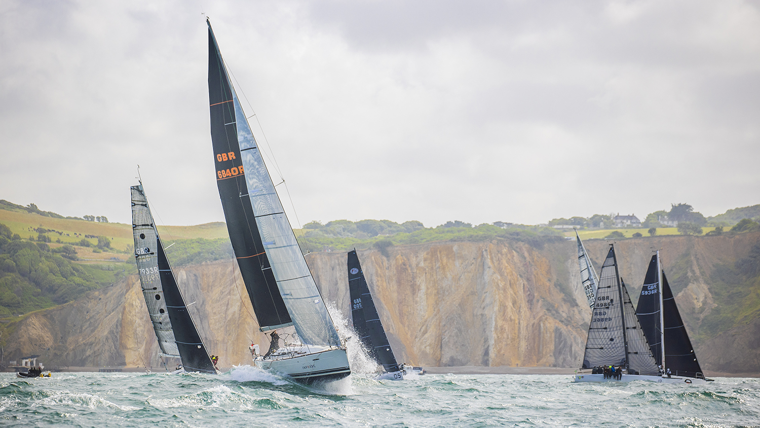 Several yachts splash through the waves during the Round the Island race