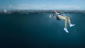 A young man is fully clothed in the open water. His face is above the water, looking up to the sky, and his arms and legs are stretched out, gently moving to help him stay afloat.
