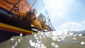 Humber lifeboat crew reaching out from the boat toward a casualty in the water