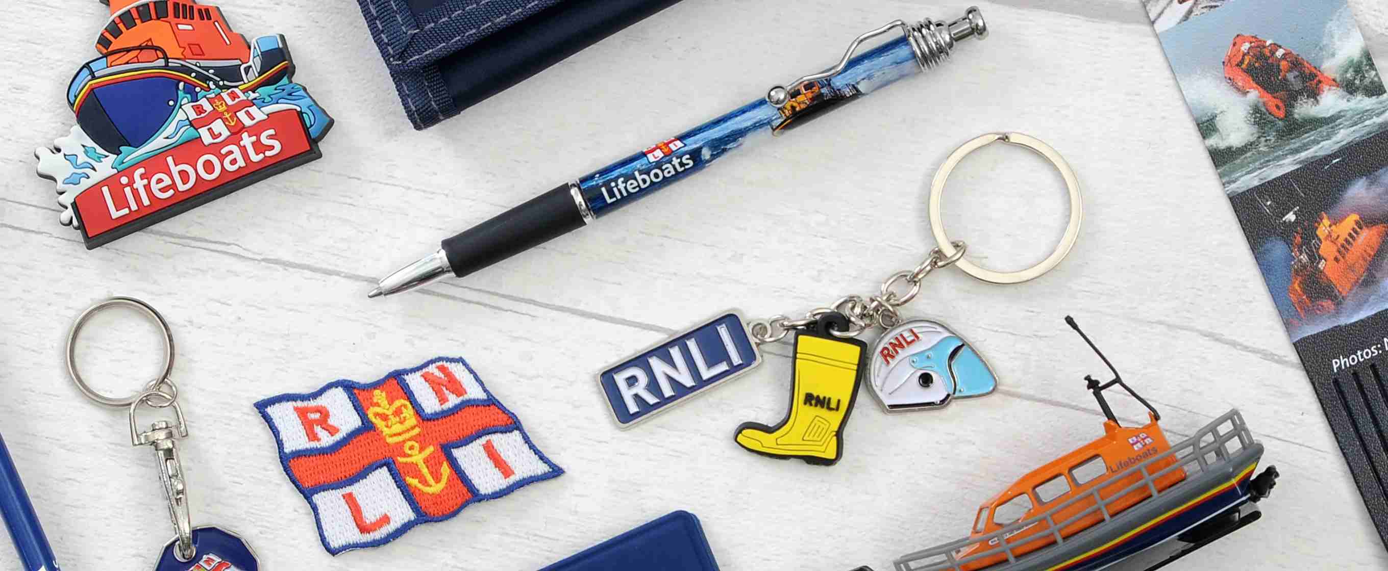 Items for sale at the RNLI shop, with RNLI logo including wallet, key chain, badge. pin, bookmark and RNLI pen