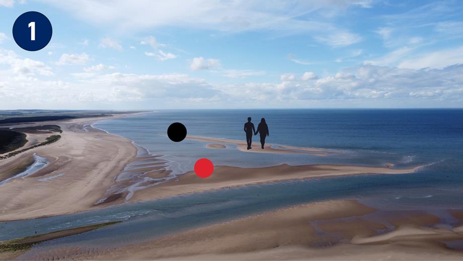 A birds-eye view of Wells beach at low tide. There is a couple walking on the sandbank that is connected to the shore but a considerable way out.