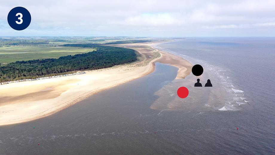 A birds-eye view of Wells Beach at high-tide. There is a couple that are now submerged in the water.