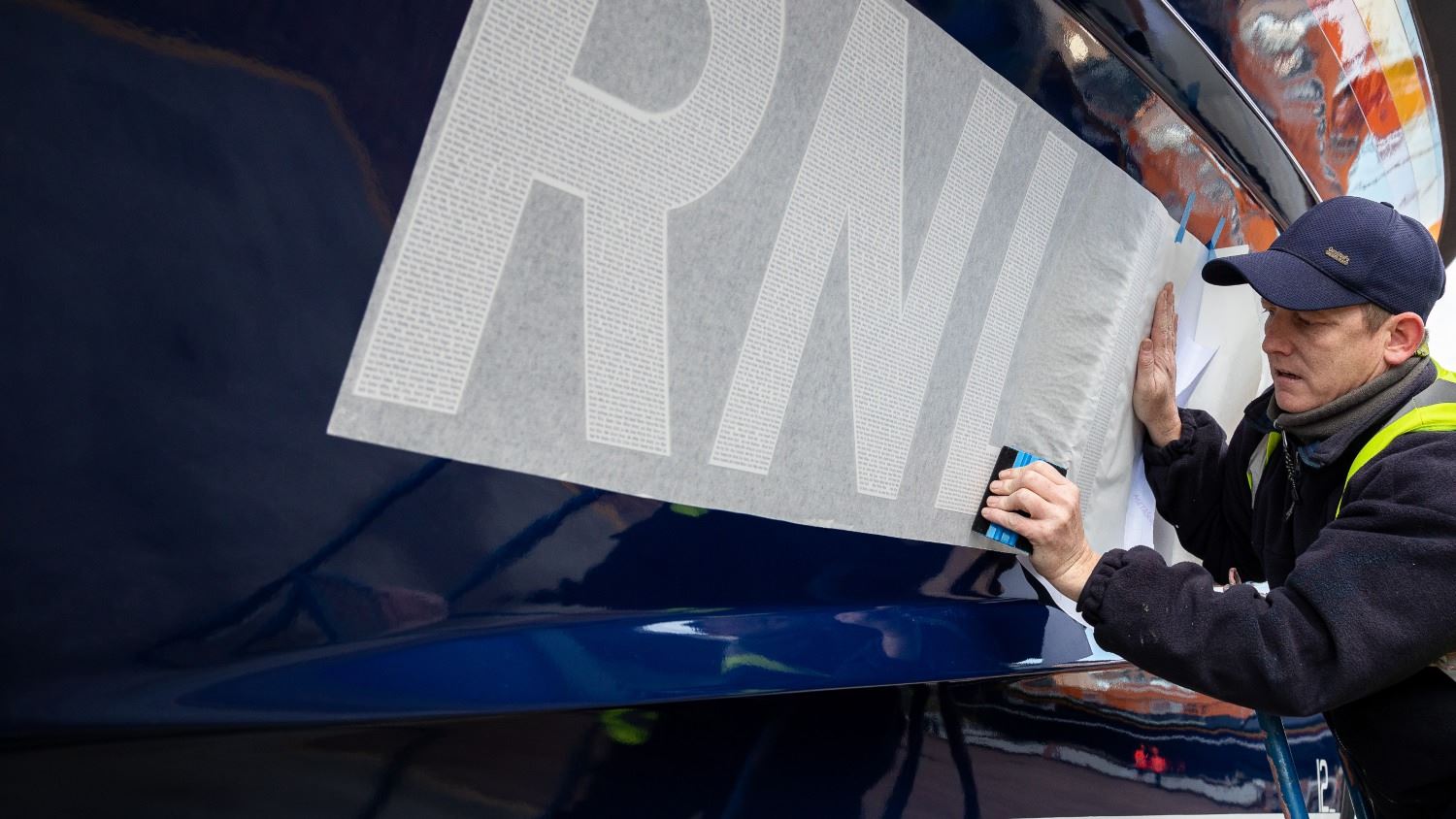 A decal with a serial number including the names of loved ones being applied to the hull of a Shannon class lifeboat.