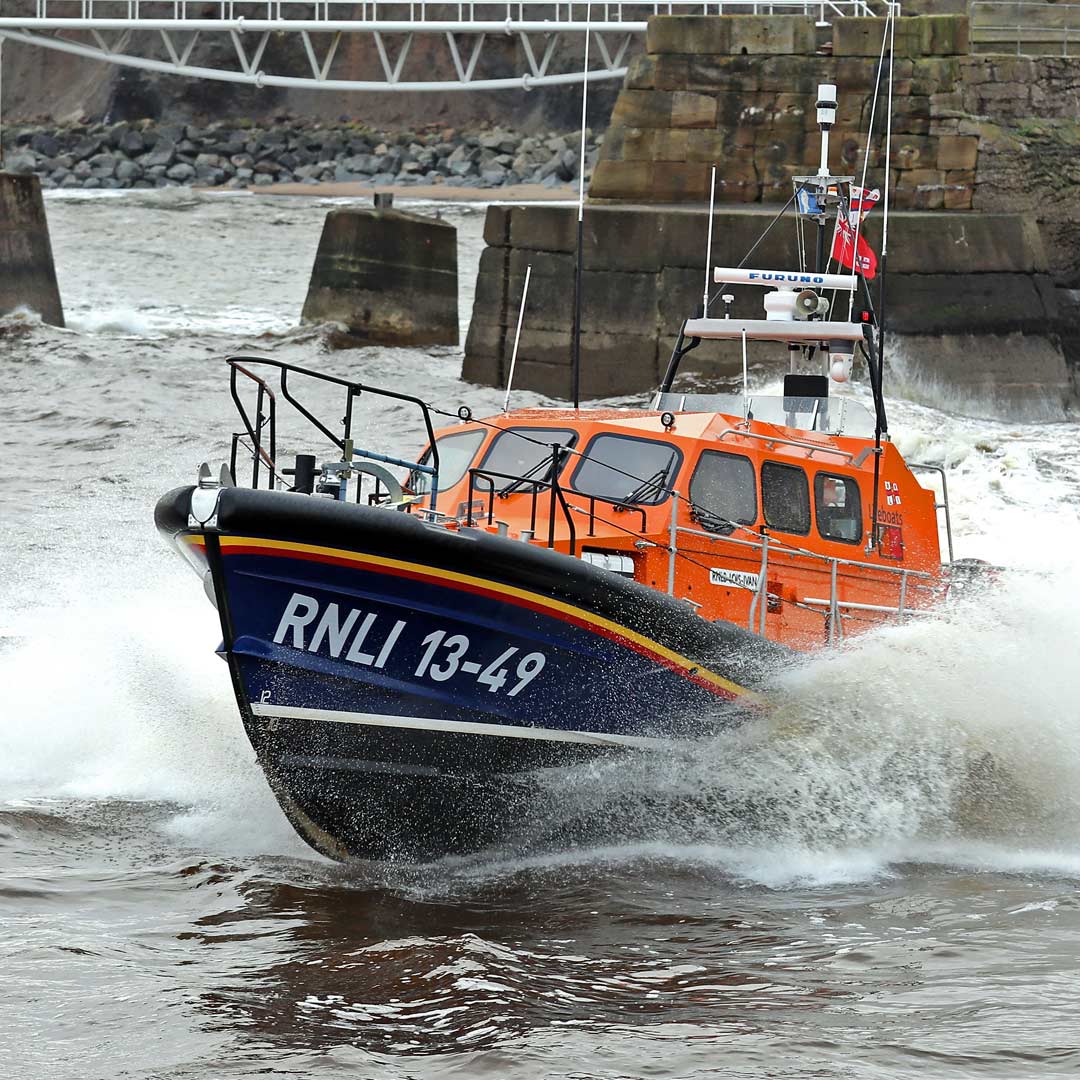 The Whitby lifeboat creating spray as it powers through the water.