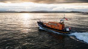 A large orange boat motors across a calm sea