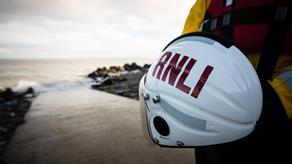A white lifeboat crew helmet with RNLI printed on it in red letters